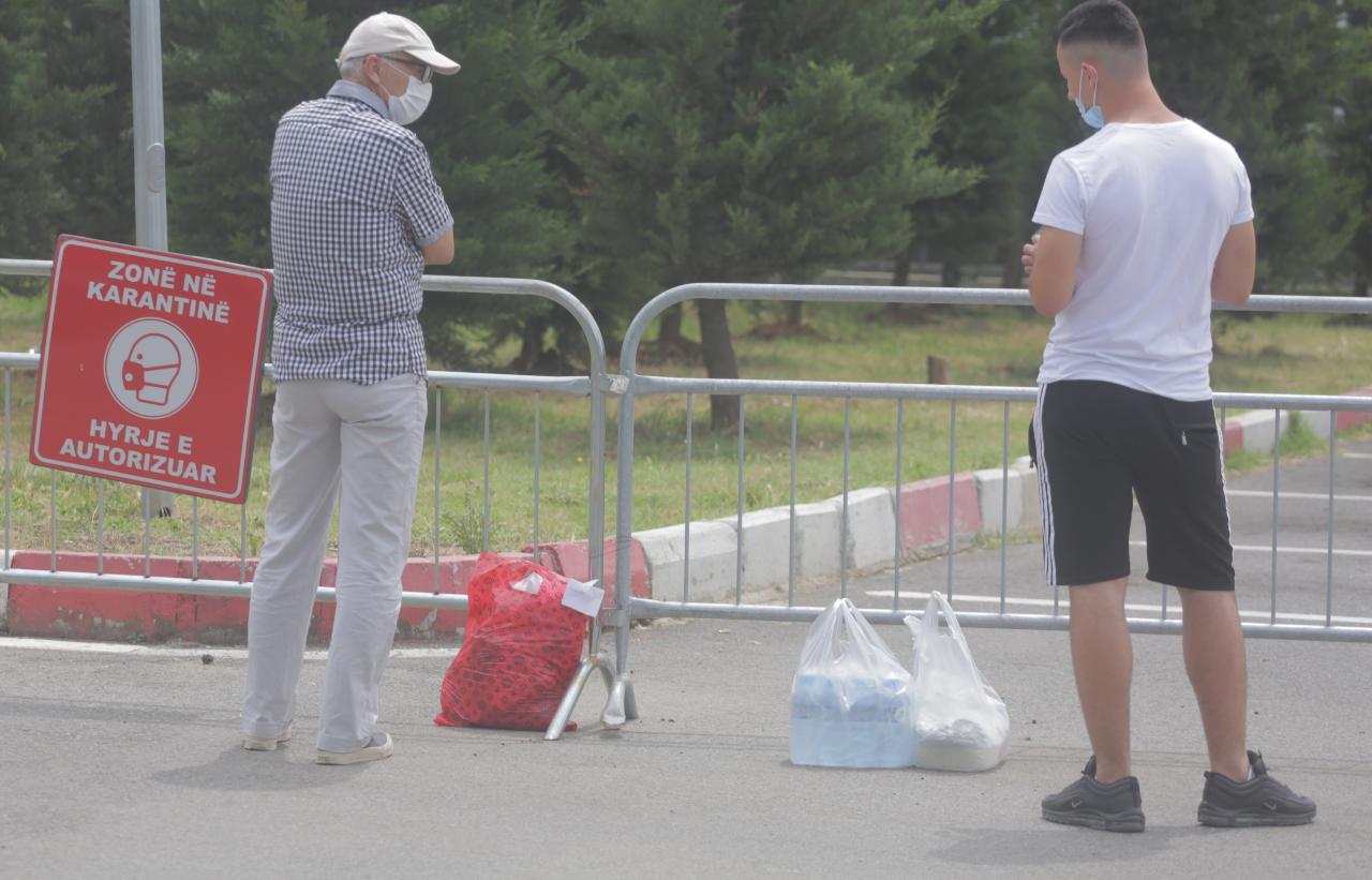 E trishtë/ Familjarët e të infekturave jashtë dyerve të Infektivit me qese rrobash dhe ushqimesh